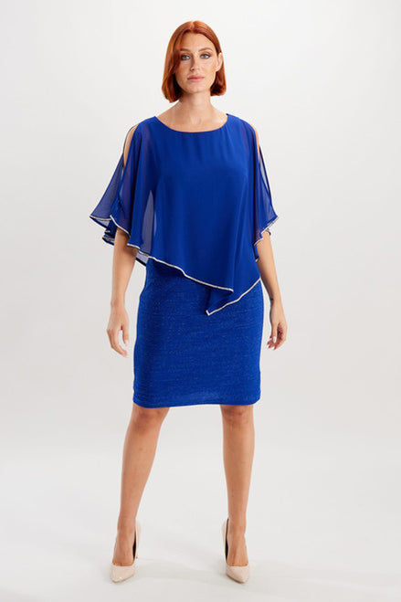 A knee-length blue dress with diamante trim on the cape overlay and a lurex skirt, modeled by a woman.