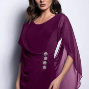 A woman wearing an elegant purple dress with a chiffon shawl and rushing detail on the sides, paired with diamond earrings.