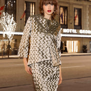 Woman in a patterned outfit standing in front of a hotel at night.