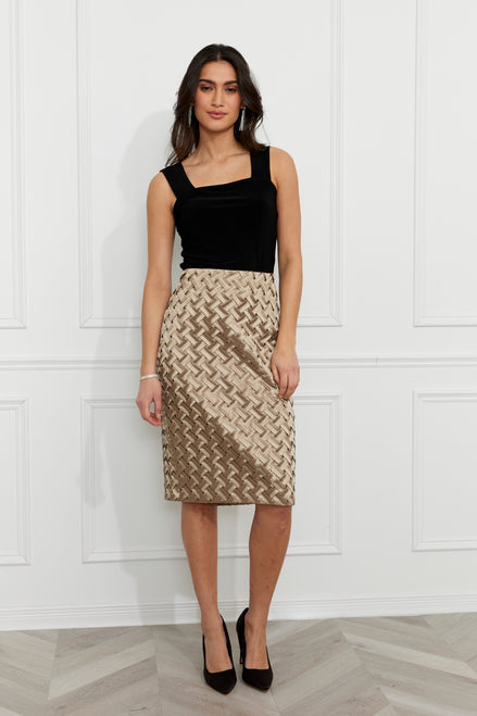 Woman wearing a black top and patterned skirt against a white paneled wall.