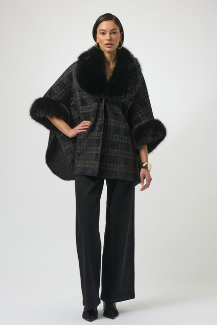 Woman wearing a black plaid poncho with fur trim on a white background