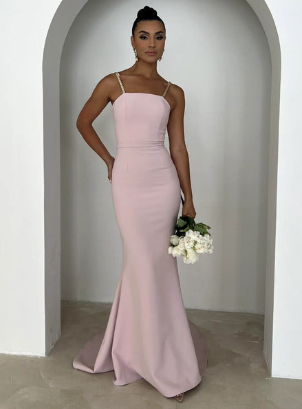 Woman in a pink gown holding flowers in a neutral setting