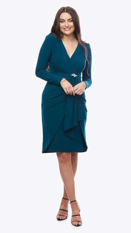 Woman wearing a teal wrap dress on a white background