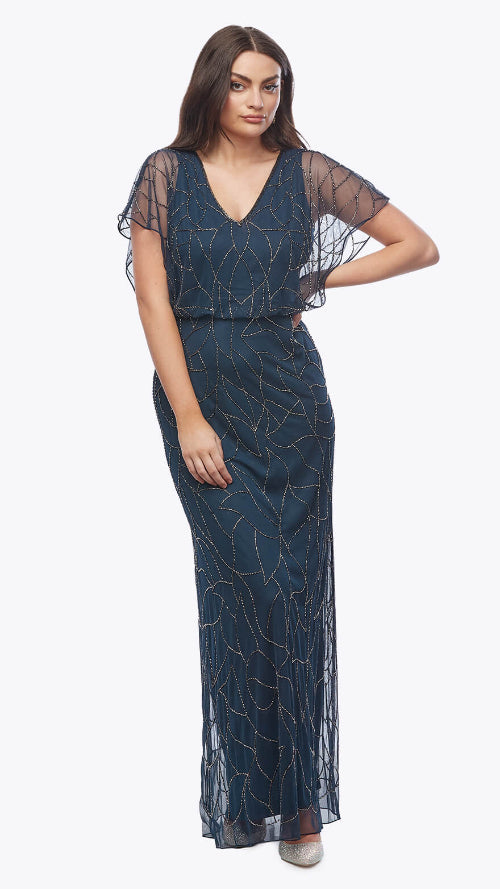 Woman wearing a dark blue evening gown with sheer sleeves on a white background