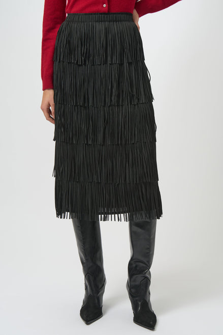 Person wearing a black fringed skirt and black boots on a white background