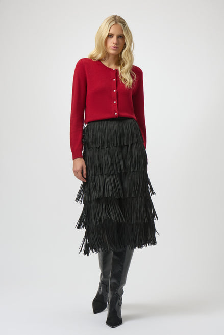 Woman wearing a red cardigan, black tiered skirt, and black boots on a white background