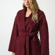 Woman wearing a burgundy coat with a white background