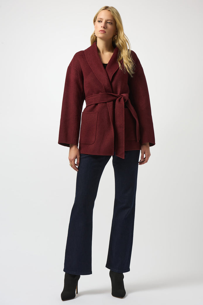 Woman wearing a burgundy coat and navy pants on a white background