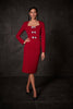 Woman wearing a red dress with silver buttons against a dark background