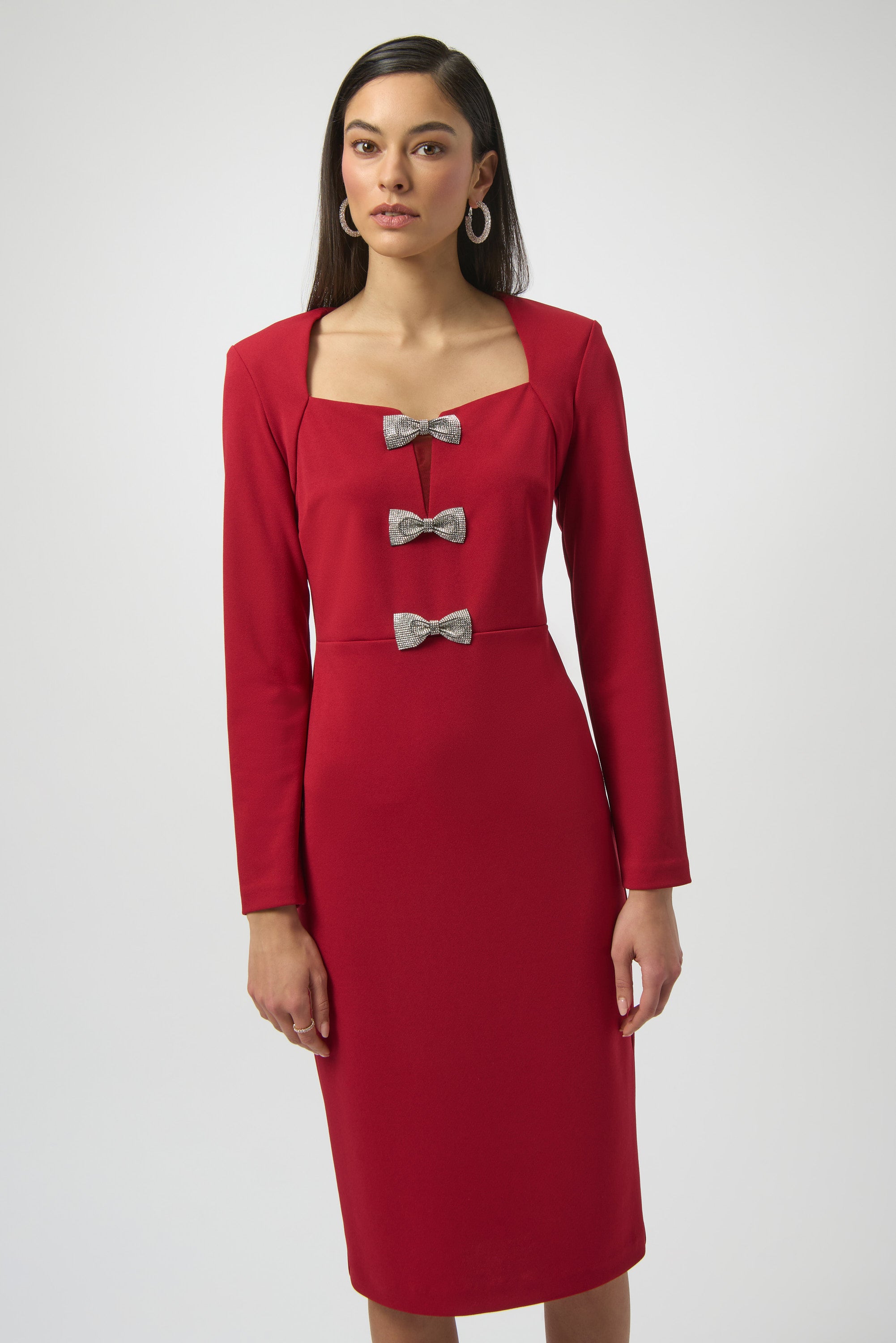 Red dress with silver bow details worn by a model on a white background