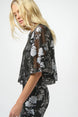 Woman wearing a black floral dress with sheer sleeves on a white background