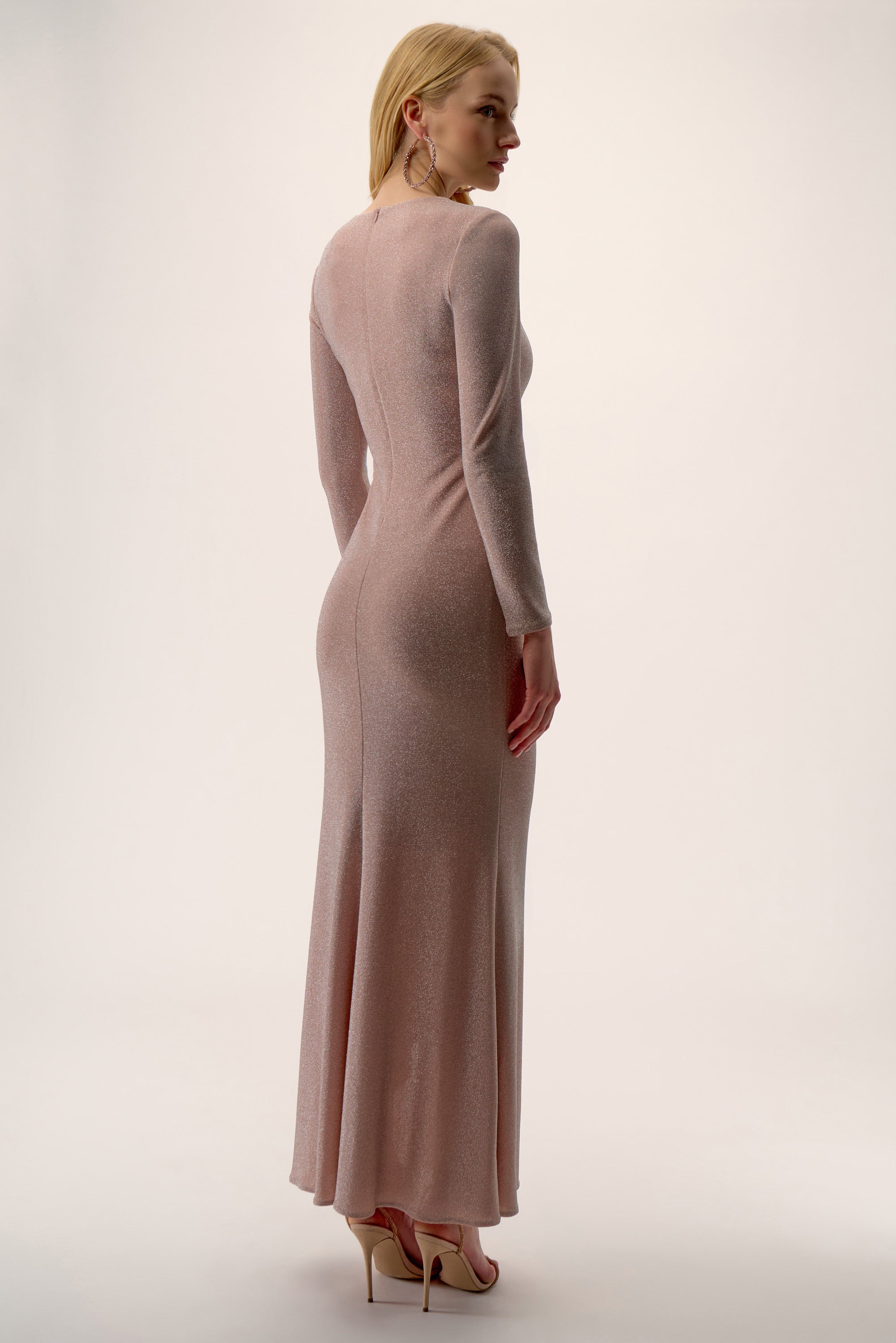 Woman wearing a long, light pink dress against a white background