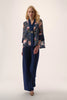 Woman wearing a floral kimono-style top and navy pants on a white background