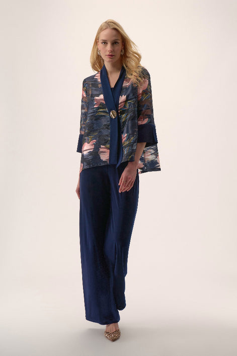 Woman wearing a floral kimono-style top and navy pants on a white background