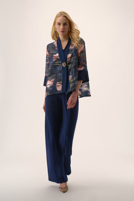 Woman wearing a floral kimono-style top and navy pants on a white background