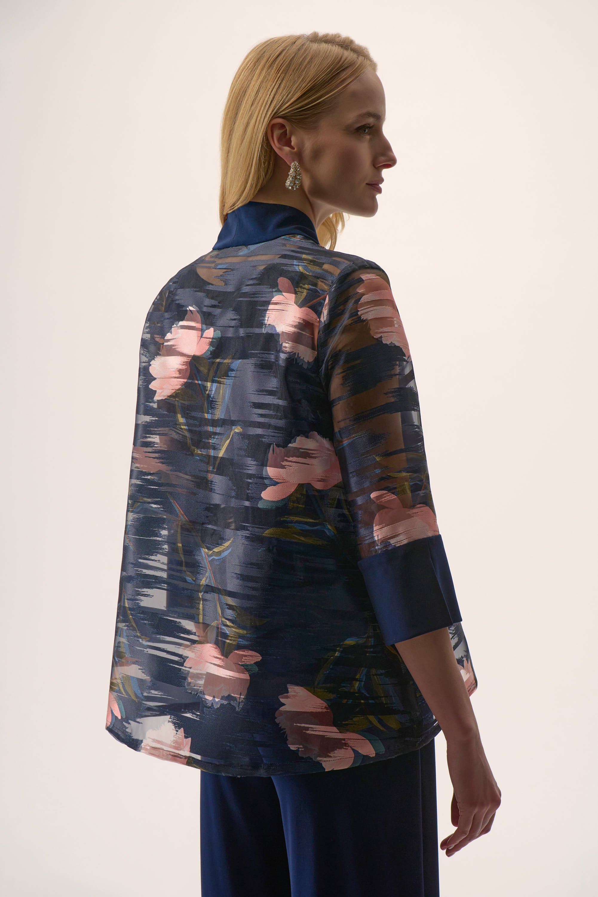 Woman wearing a floral patterned jacket with a plain background
