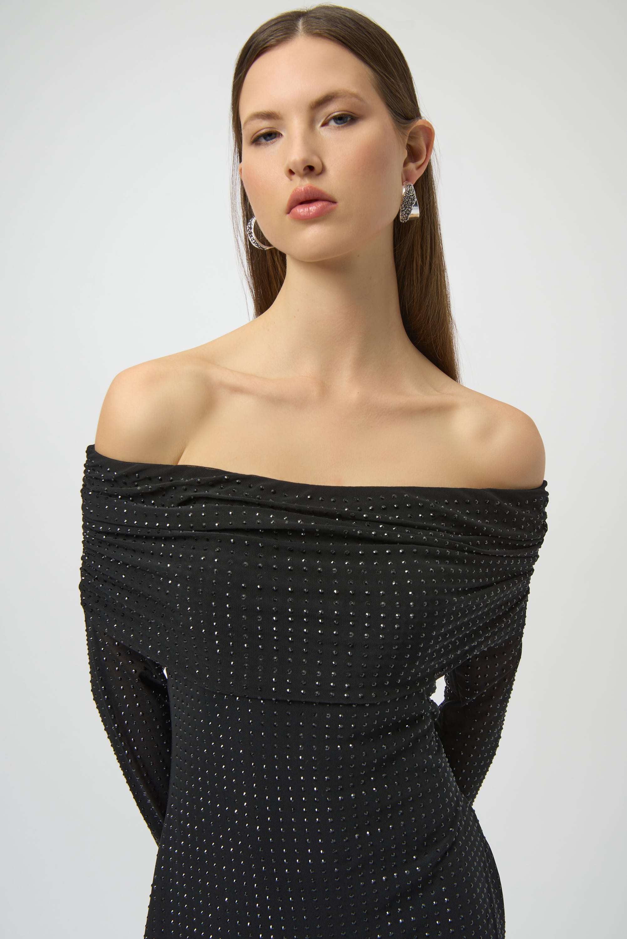 Woman wearing a black off-shoulder dress with a white background