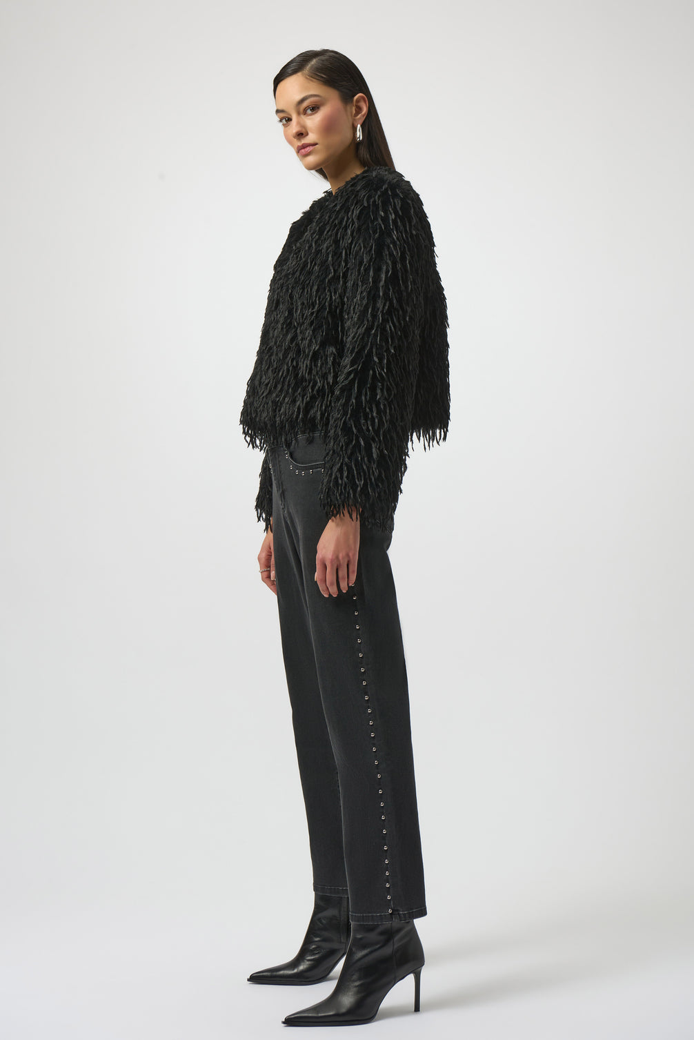 Woman wearing a black fringed jacket, black pants, and black boots on a white background