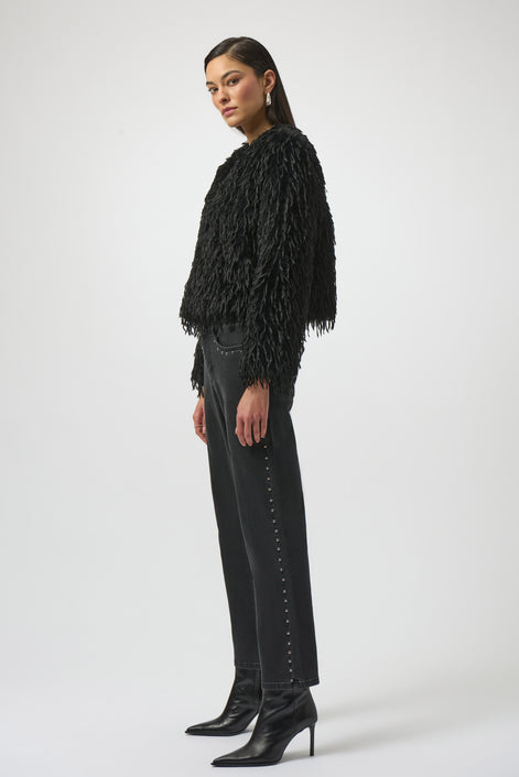 Woman wearing a black fringed jacket, black pants, and black boots on a white background