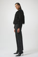 Woman wearing a black fringed jacket, black pants, and black boots on a white background