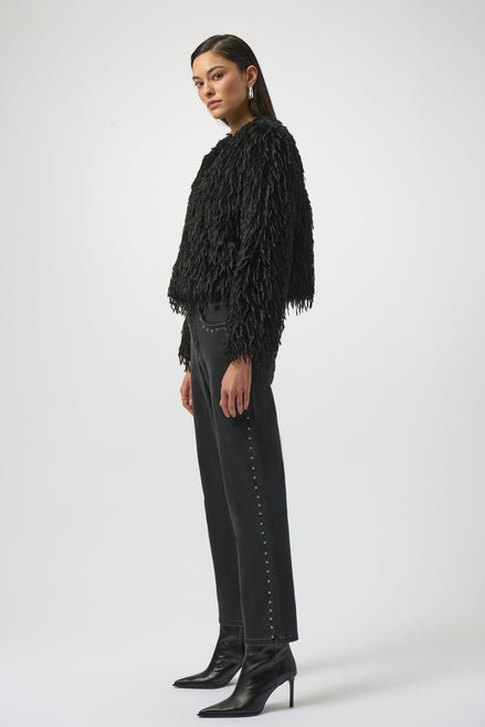 Woman wearing a black fringed jacket, black pants, and black boots on a white background