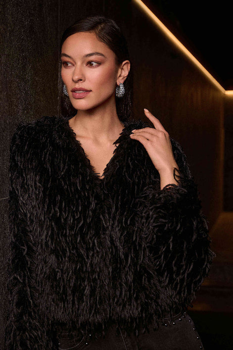 Woman wearing a black textured top against a dark background