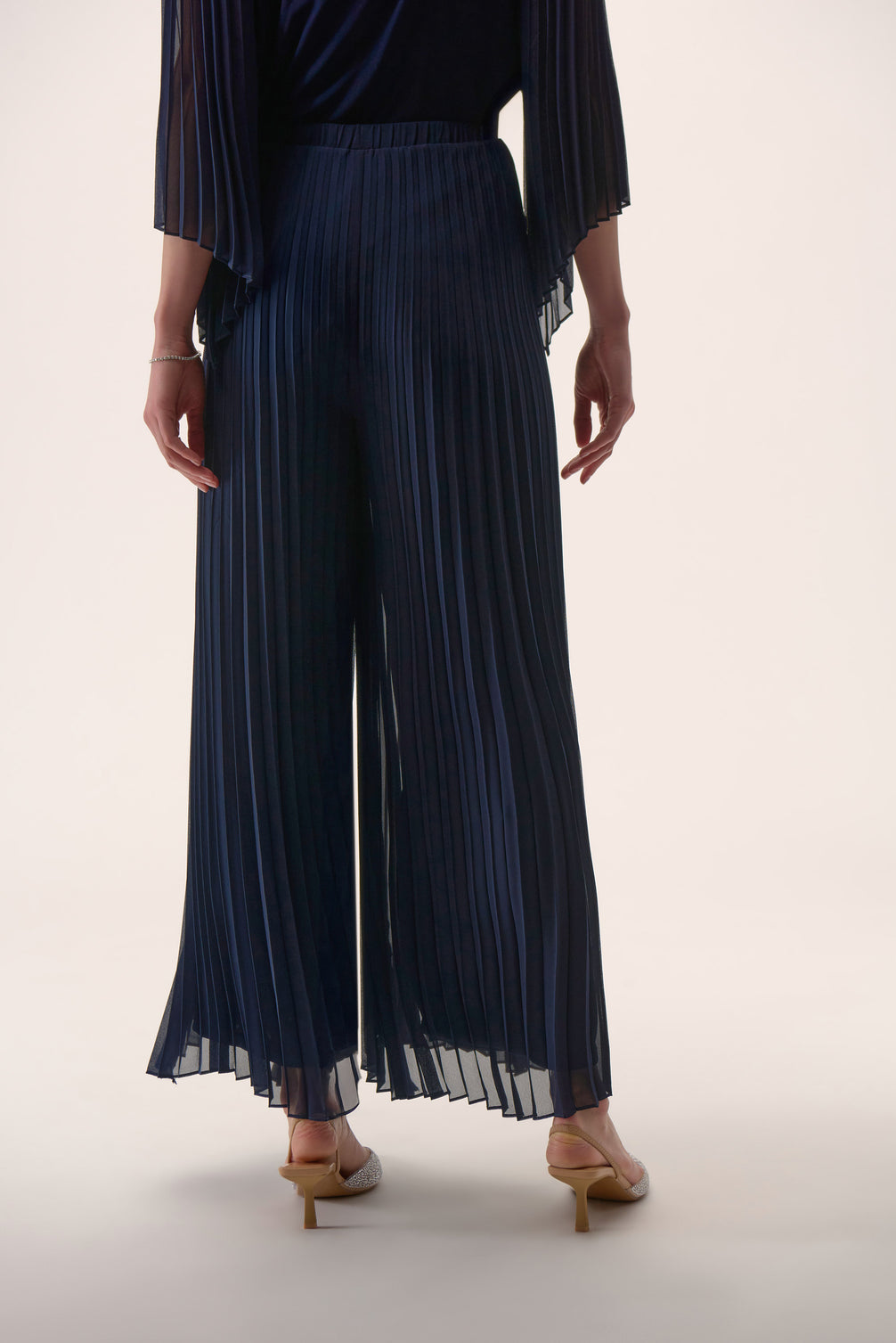 Navy pleated pants worn by a person on a white background