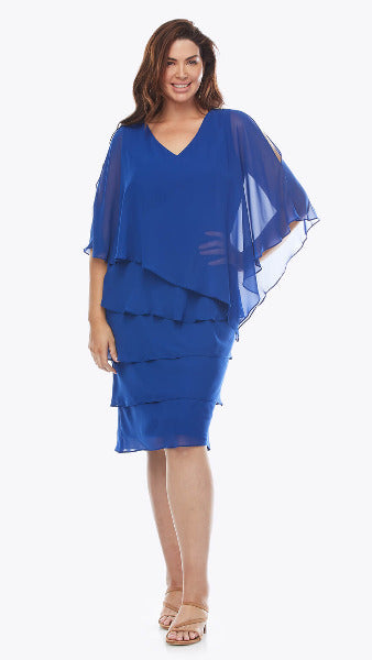 A woman in an electric blue dress with chiffon ruffled layers and a V-neckline. The dress has a knee-length skirt and a flowing overlay.
