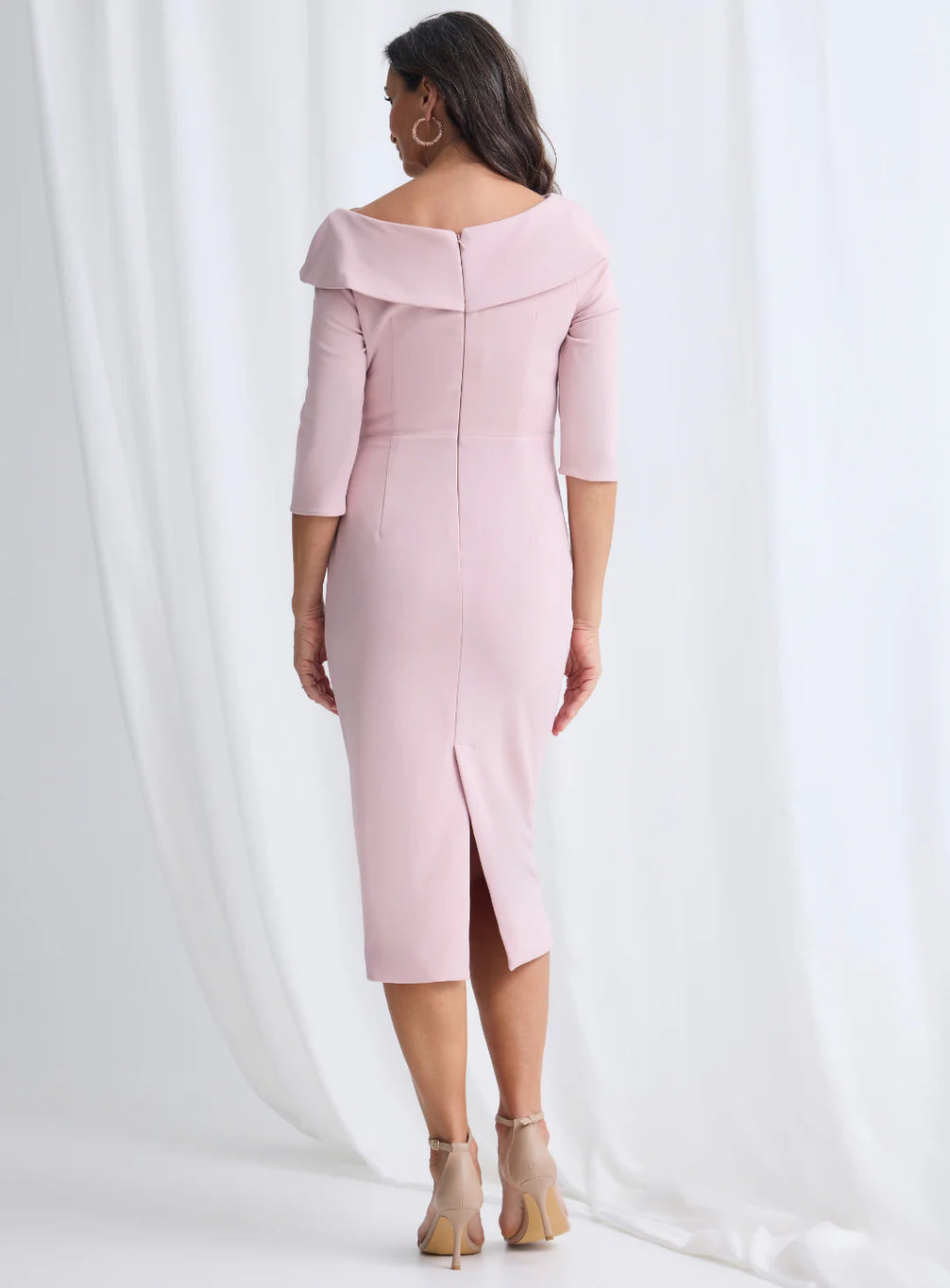 Woman wearing a pink off-shoulder dress with a slit on a white background