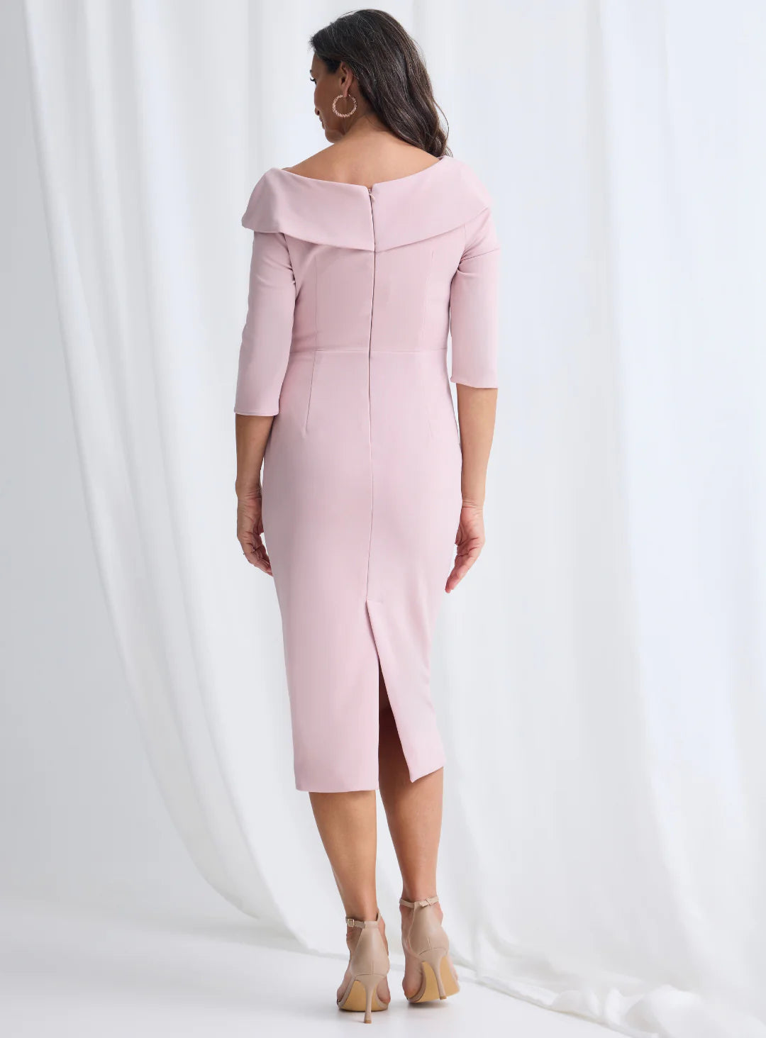 Woman wearing a pink off-shoulder dress with a slit on a white background
